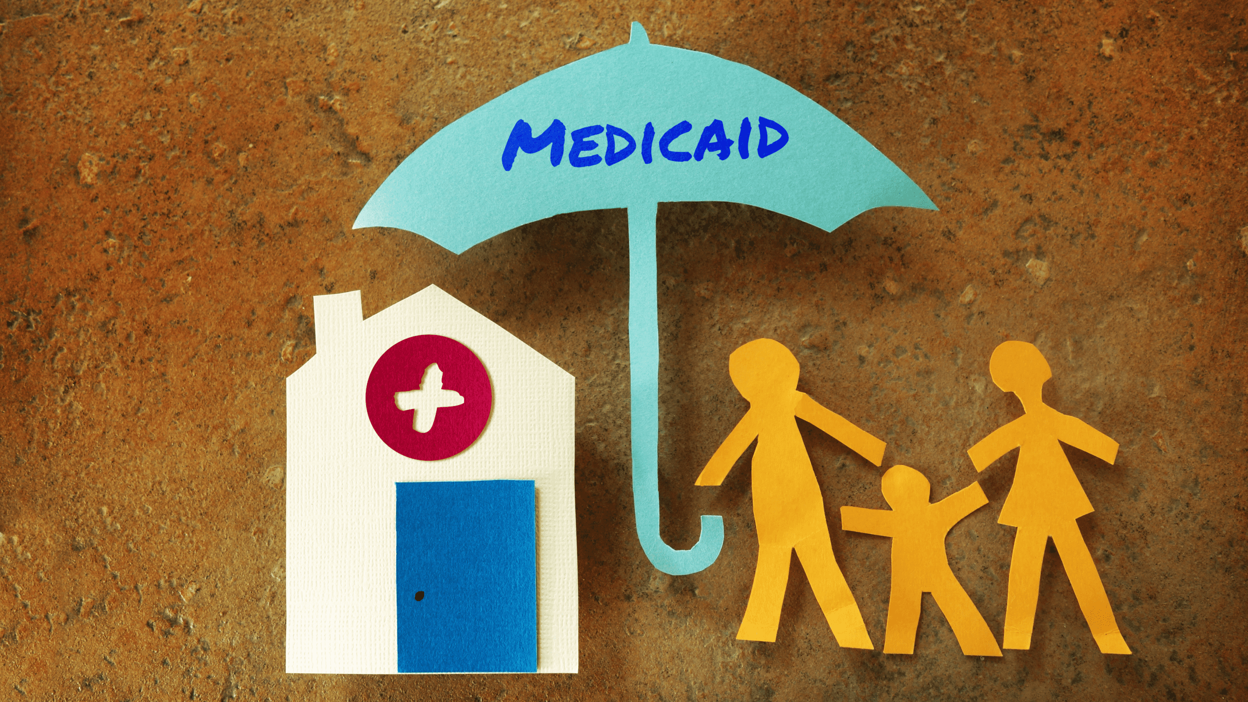 stock photo of paper cutouts depicting a family under an umbrella with Medicaid written on it
